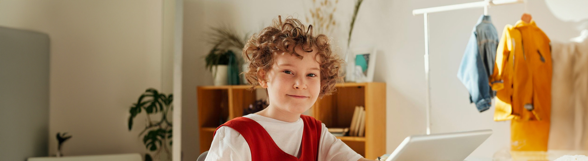 A kid using a laptop looks at the camera.